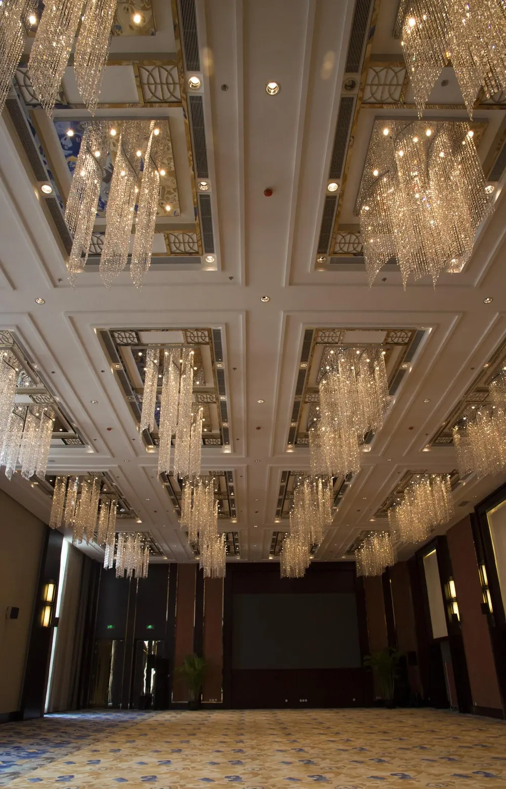 Crystal chandeliers hanging from a coffered ballroom ceiling